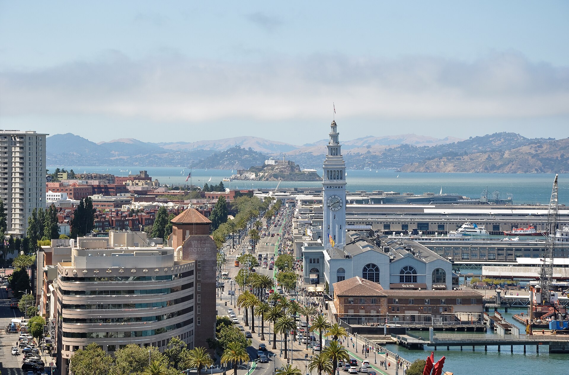 The Embarcadero looking north — Ferry Building clock, the piers, and the island on the horizon.